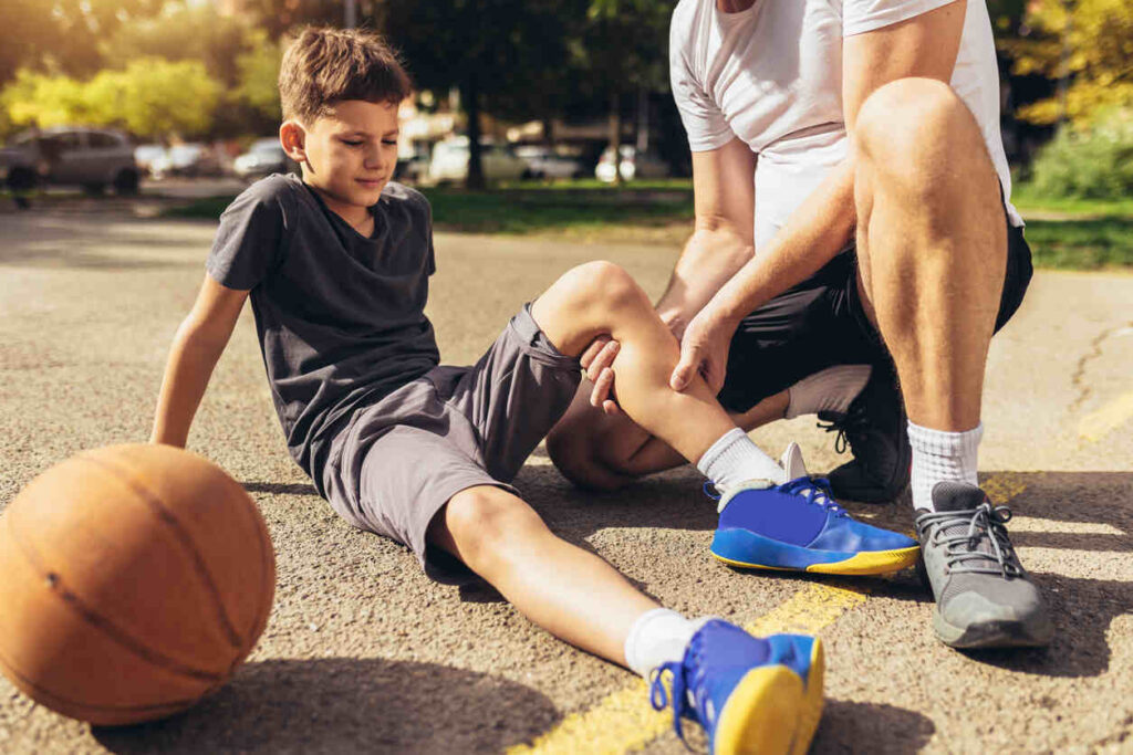 Alt text: "A coach assisting an injured child after a basketball injury, reflecting the legal implications of suing a coach for sports-related injuries.
