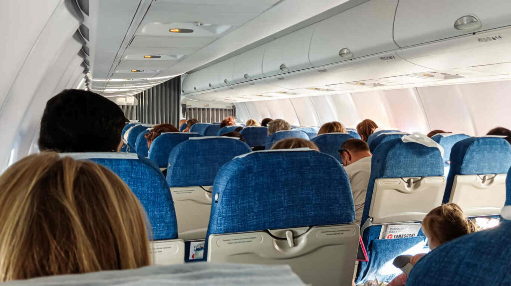 Flight attendants and passengers in an airplane cabin, highlighting potential injury risks for flight attendants, such as turbulence, heavy lifting, and navigating crowded aisles.