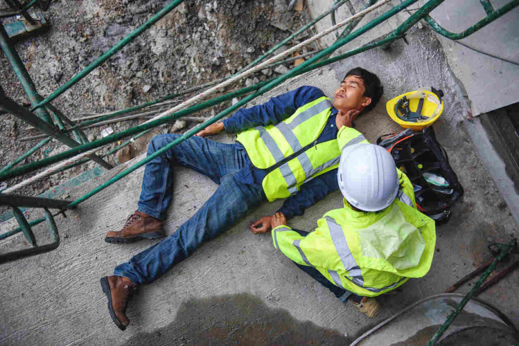 A construction worker being assisted after an injury on scaffolding, highlighting common causes of scaffolding injuries such as falls, equipment failure, and lack of safety measures.