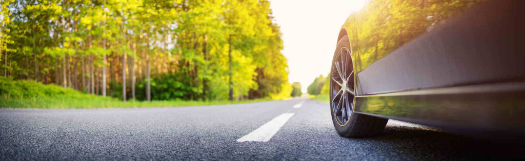 A scenic road with a car parked on the side, representing summer road safety during the 100 deadliest days of summer, when accidents often spike due to increased travel and risky driving behaviors.