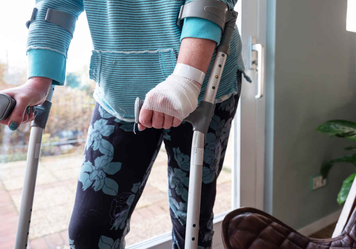 Person with a bandaged hand using crutches, symbolizing a catastrophic injury and highlighting the importance of considering future medical needs in settlement claims.