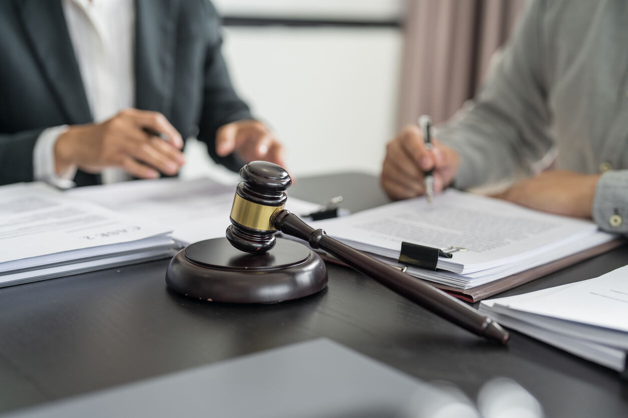 A lawyer consulting with a client, with a gavel on the table, representing the services of a personal injury lawyer in Amesbury.