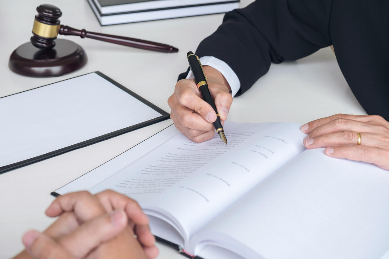 A lawyer signing legal documents at a desk, with a gavel and law books in the background, representing a personal injury lawyer in Lowell, Massachusetts.